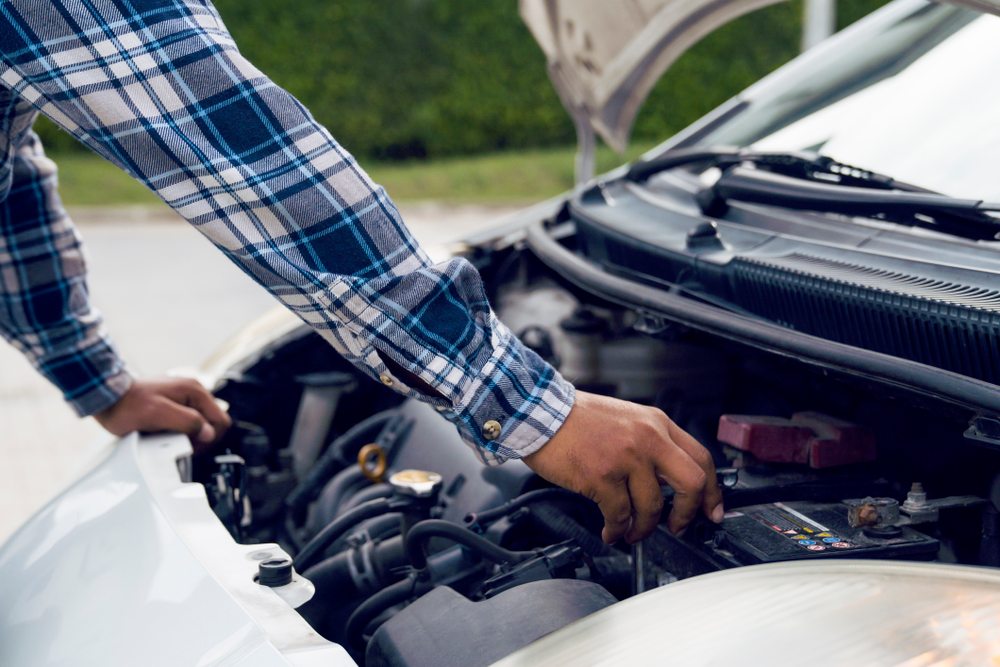 En man som kollar bilmotorn